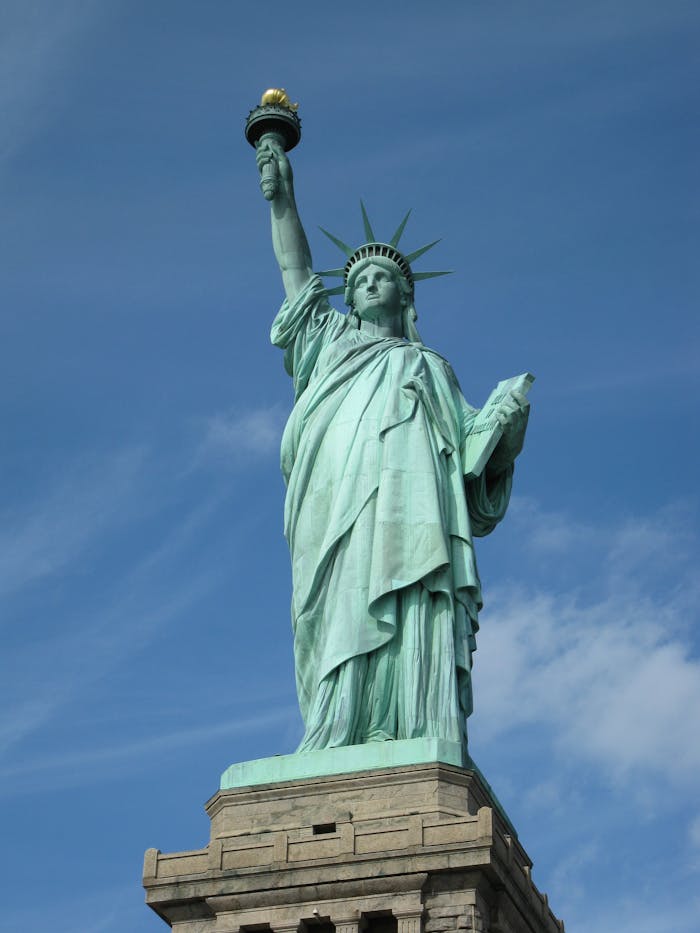 services-01 The Statue of Liberty serves as a symbol of freedom against a clear blue sky in New York City.